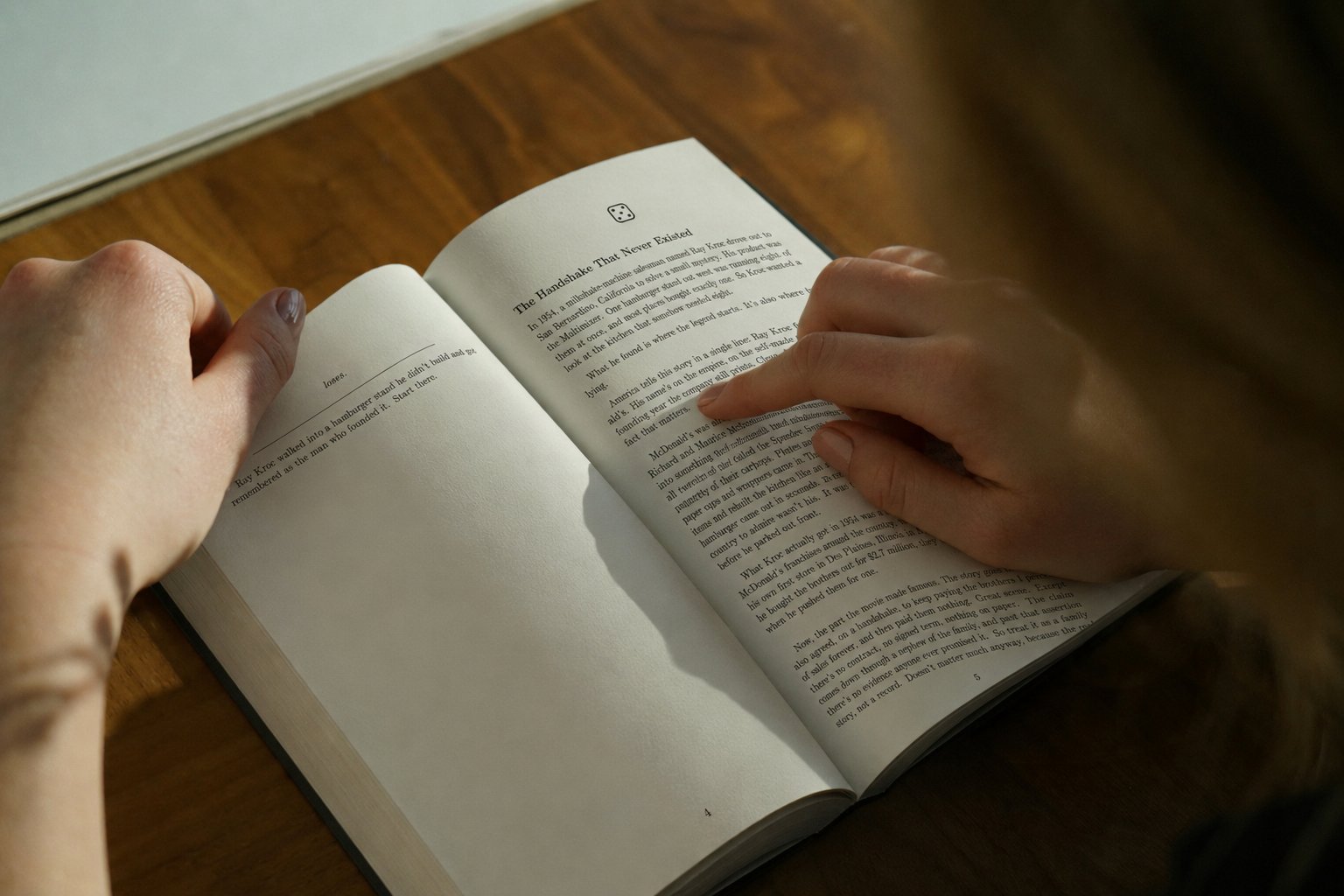 Le chapitre 1 dans les mains d'une lectrice : l'emblème du dé, le titre, le texte justifié.