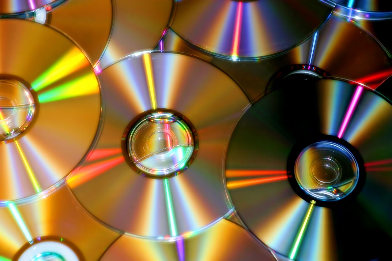 Un amas de disques compacts renvoyant des traînées de lumière arc-en-ciel — l'objet du quotidien dont les dimensions cachent une dispute vieille de 40 ans. Crédit : happyend / Pexels (libre d'utilisation)
