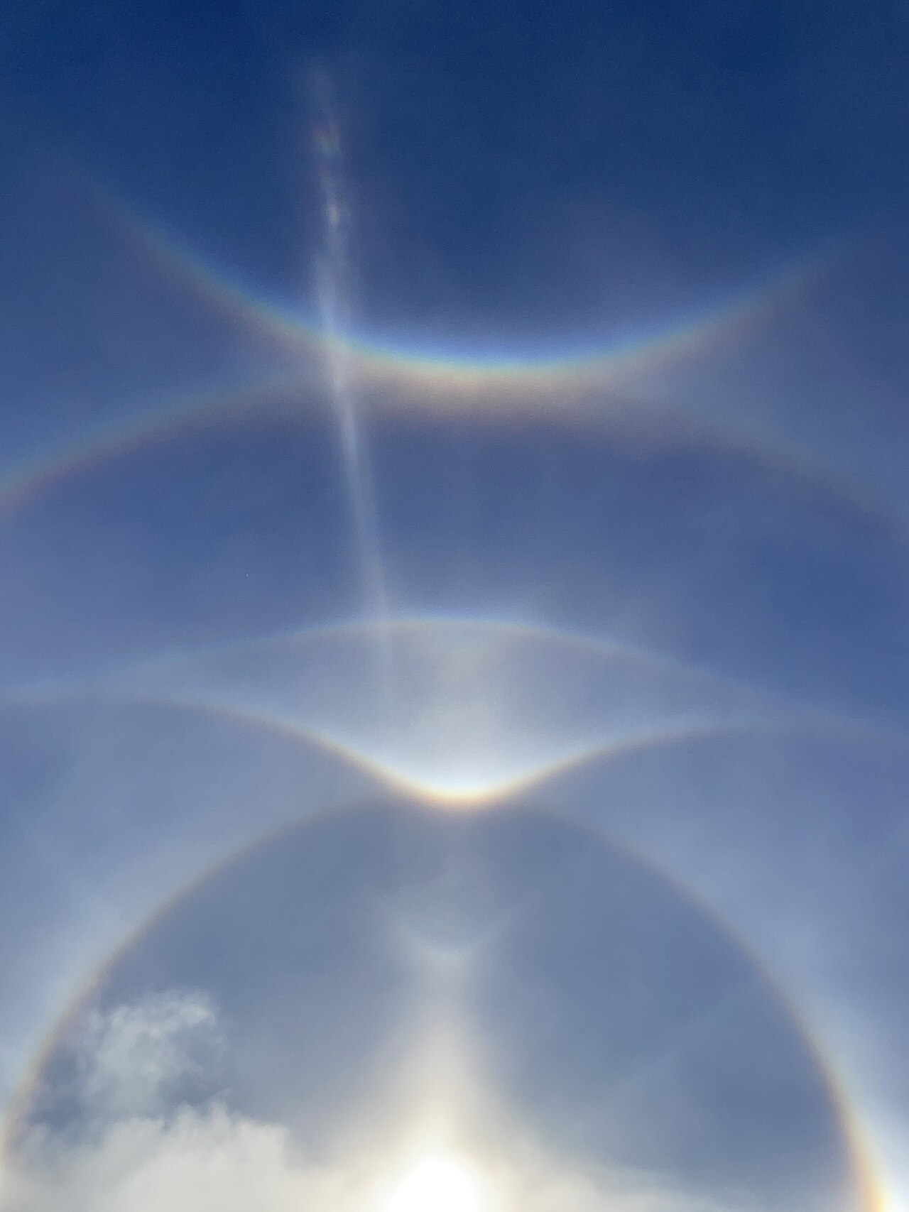 Un grand déploiement de halos de glace, avec l'arc circumzénithal lumineux qui culmine tout en haut — ces arcs font partie d'une famille entière. — Crédit : Trulyamayed / Wikimedia Commons (CC0, domaine public)