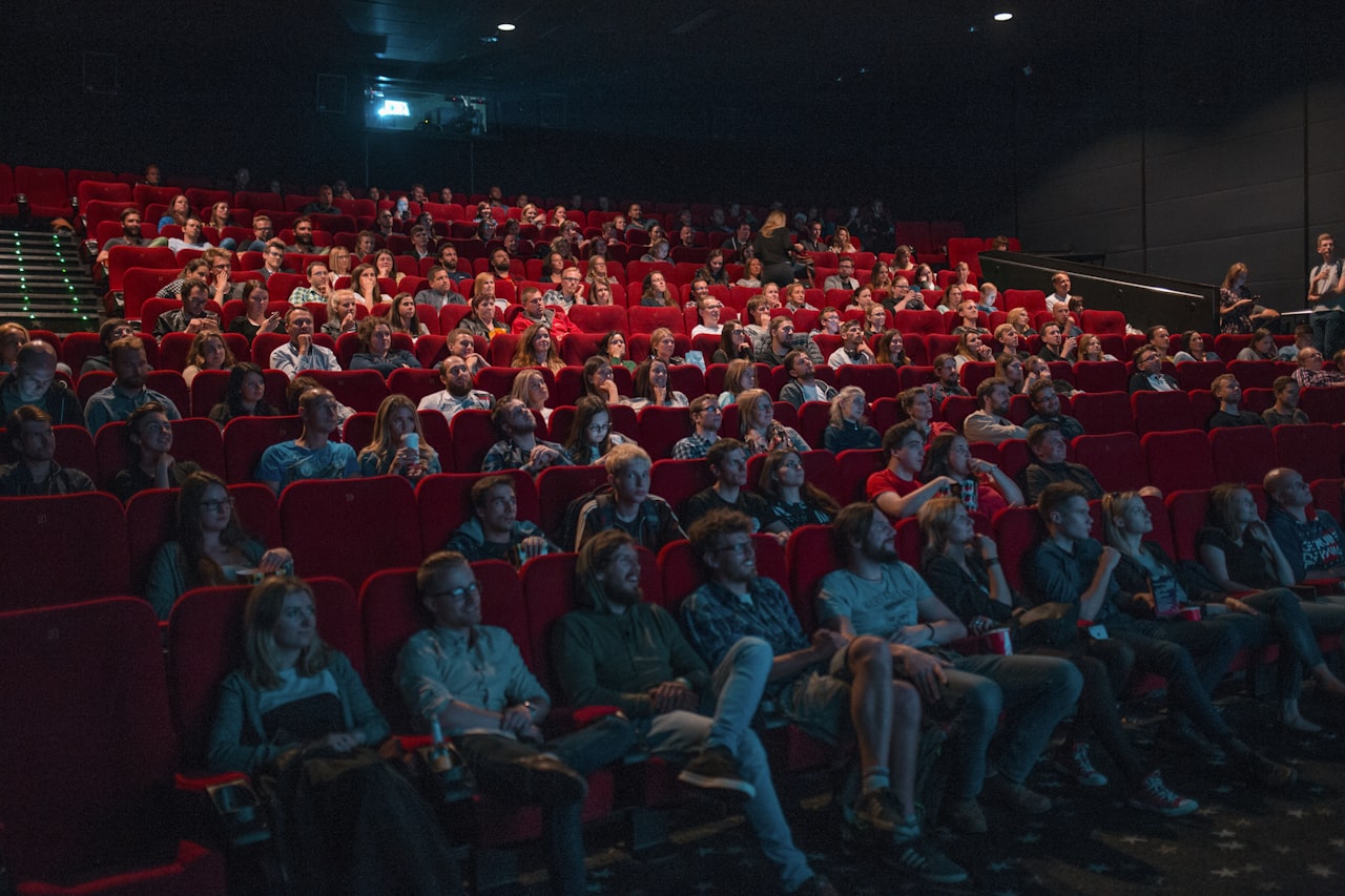 Une salle de cinéma bondée dans le noir — Oppenheimer a transformé un format de projection vieux de 70 ans en événement à guichets fermés. — Crédit : Krists Luhaers / Unsplash