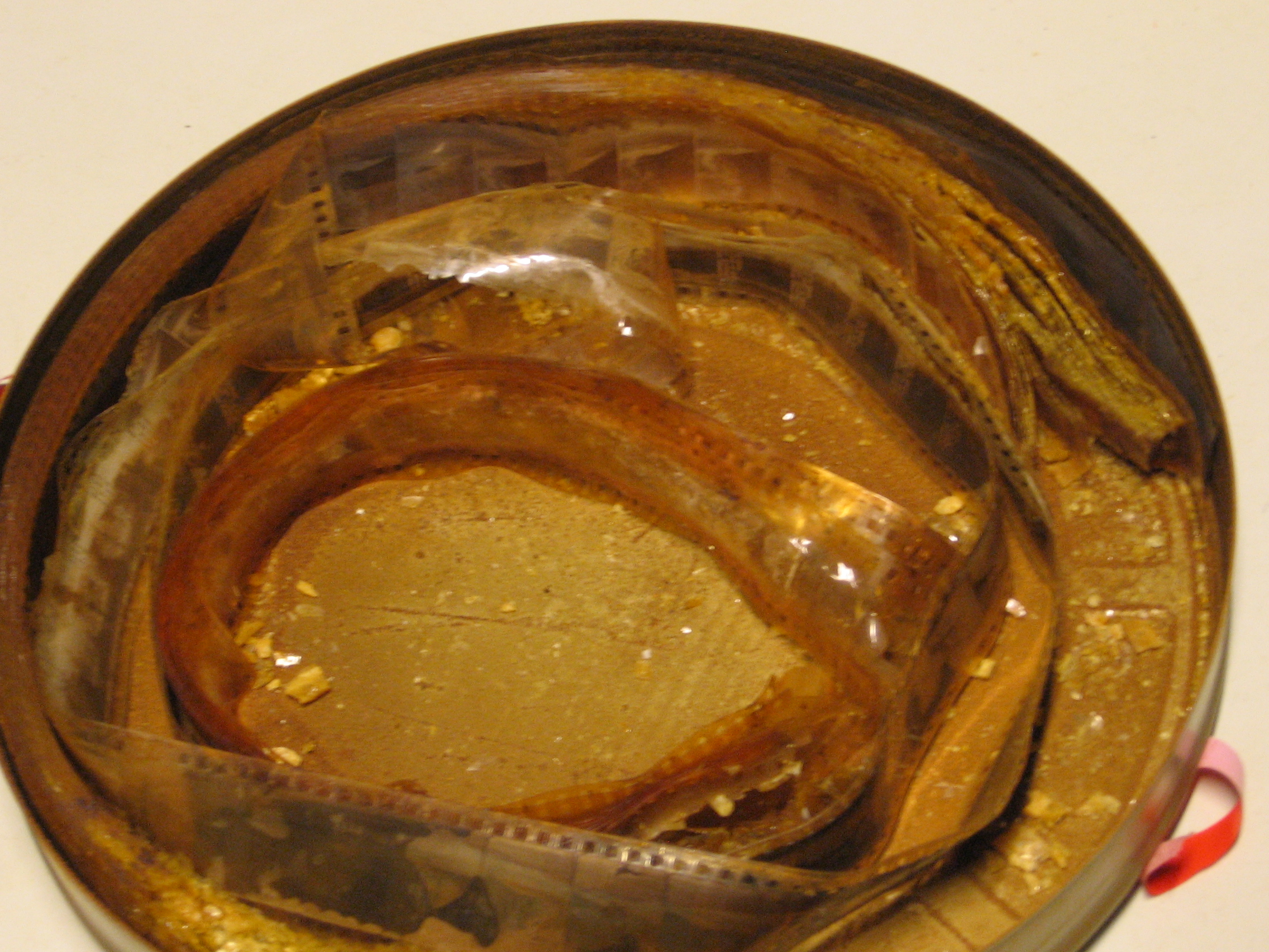 Pellicule au nitrate décomposée sortie d'une boîte : l'image en argent disparue, le support cloqué et gondolé avant de tomber en poudre — Crédit : Hansmuller, EYE Film Institute Netherlands (CC BY-SA 4.0, Wikimedia Commons)