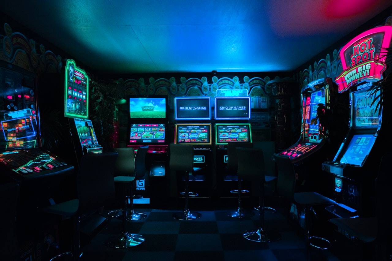 Une salle d'arcade plongée dans le néon — le genre d'endroit où la légende de Polybius aurait pris racine. — Crédit : Carl Raw sur Unsplash (Licence Unsplash)