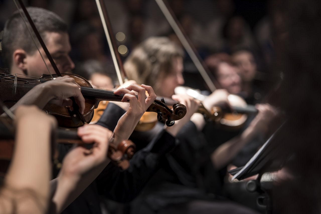 Des violonistes dans un pupitre de cordes, le genre d'ensemble qui vit ou meurt selon une hauteur de référence partagée. — Crédit : Larisa Birta, Unsplash